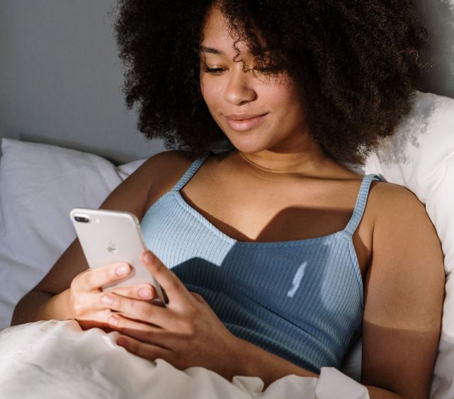 woman using iphone in bed